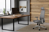 Silla de oficina ergonómica gris con reposacabezas junto a un escritorio rústico de madera de NIHM Workplace.